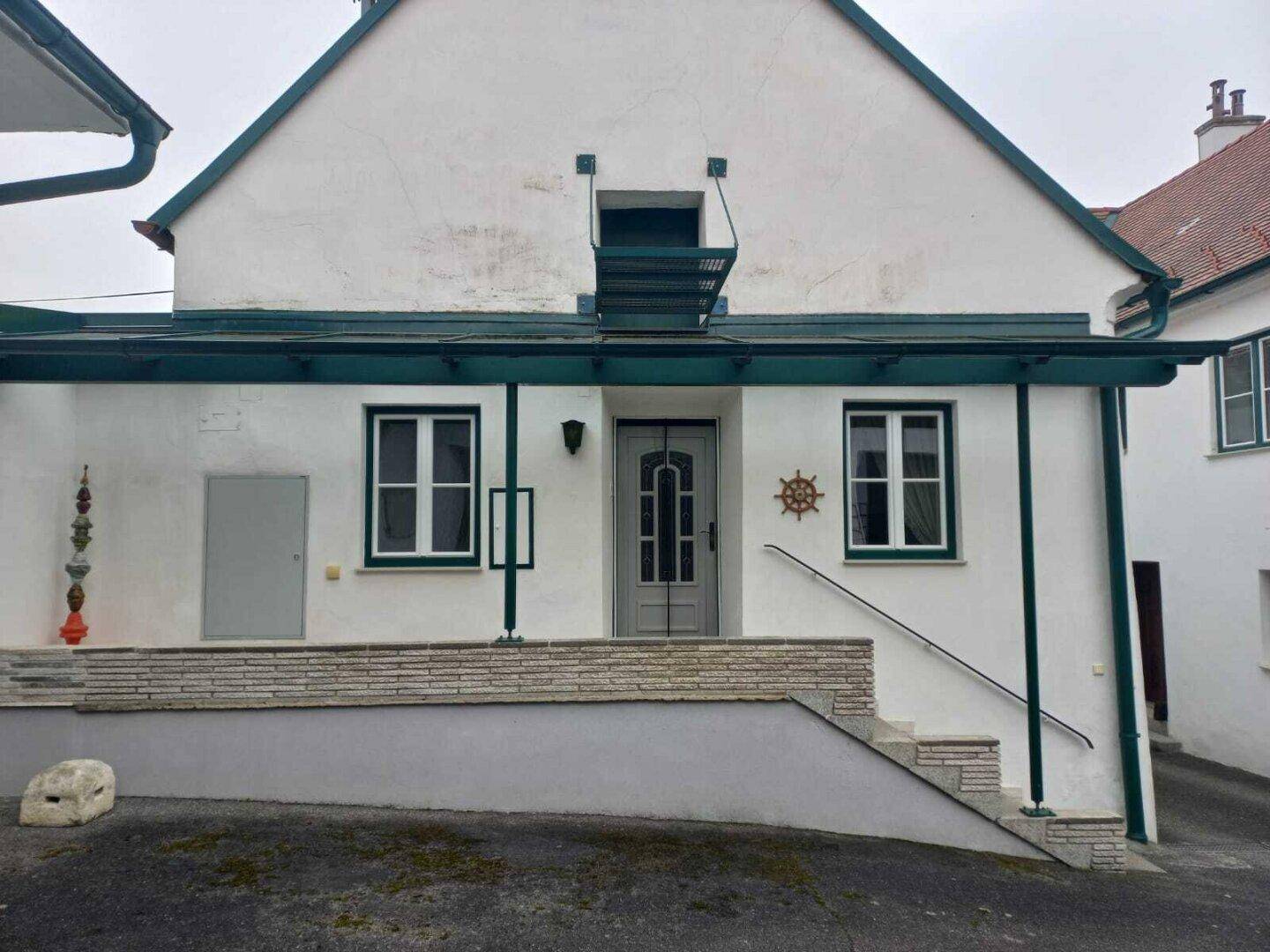 Eingangsbereich des Hauses mit einer überdachten Veranda und einer Treppe zum Haupteingang.