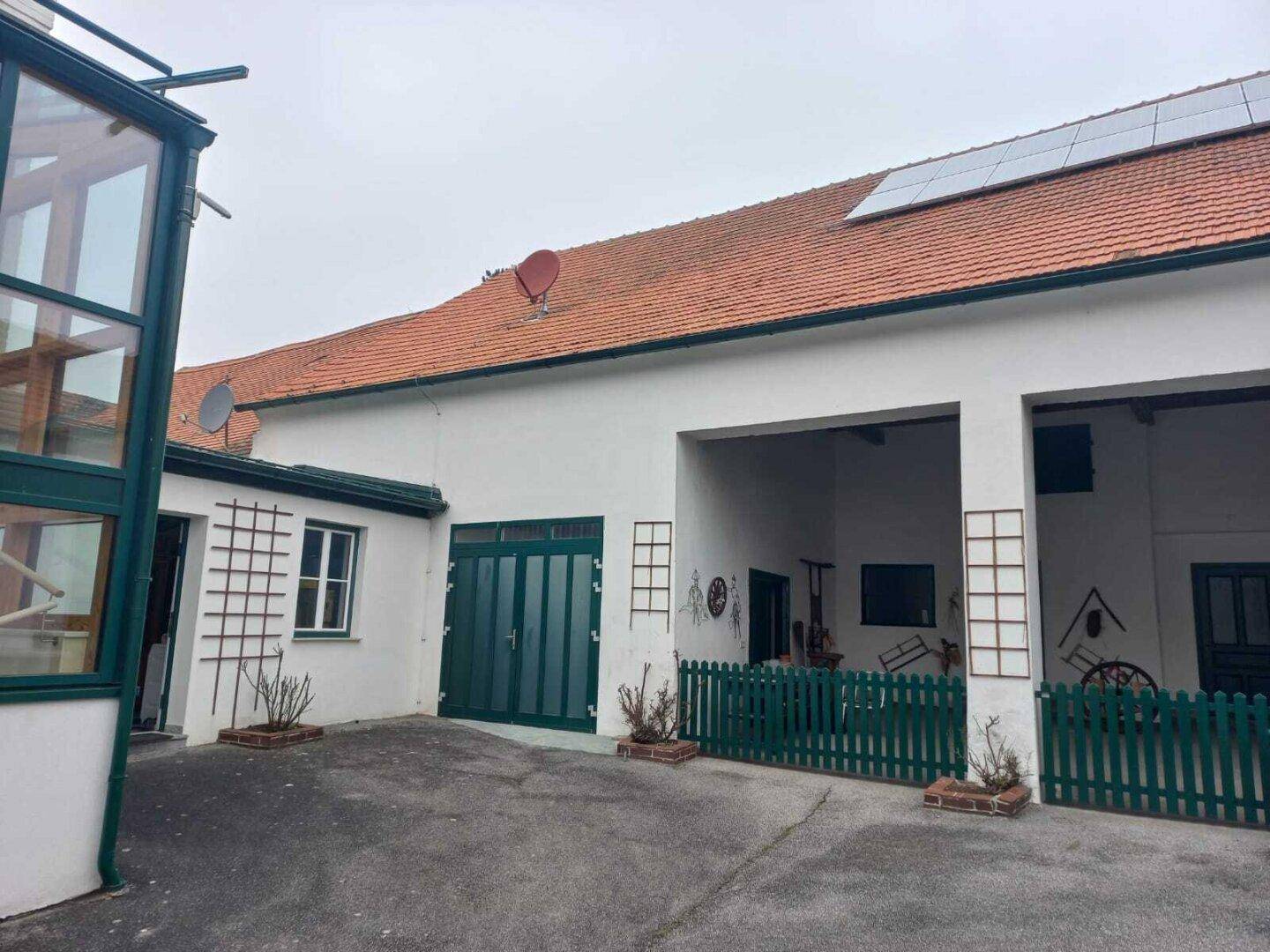 Innenhof mit Blick auf den Glasanbau und die Solarpaneele auf dem roten Ziegeldach.
