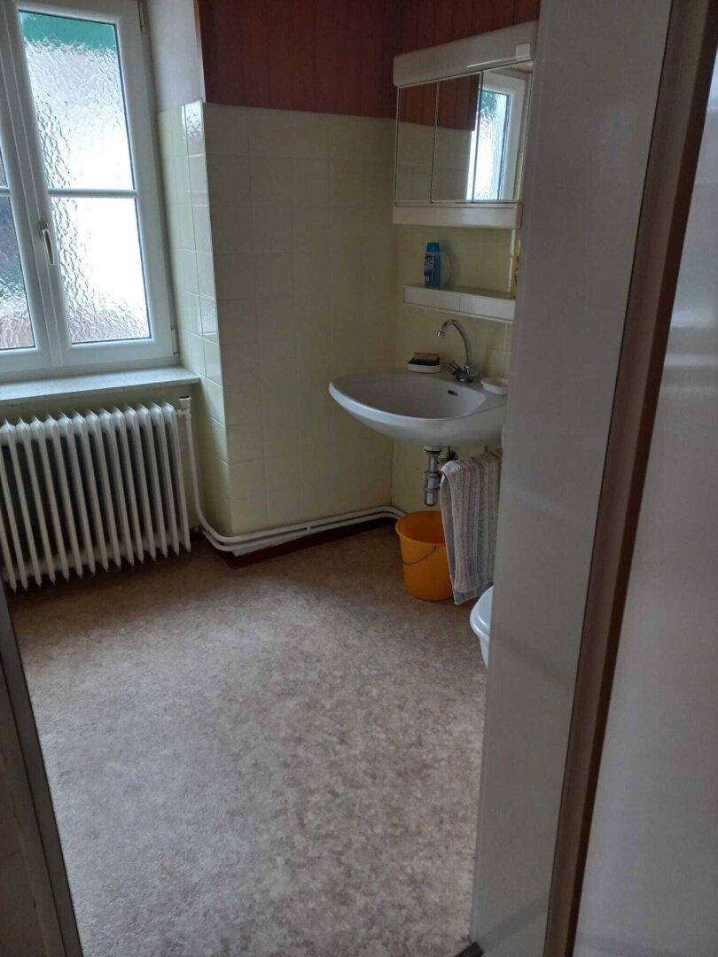 Badezimmer mit Waschbecken, Spiegelschrank und einem Fenster für Tageslicht.