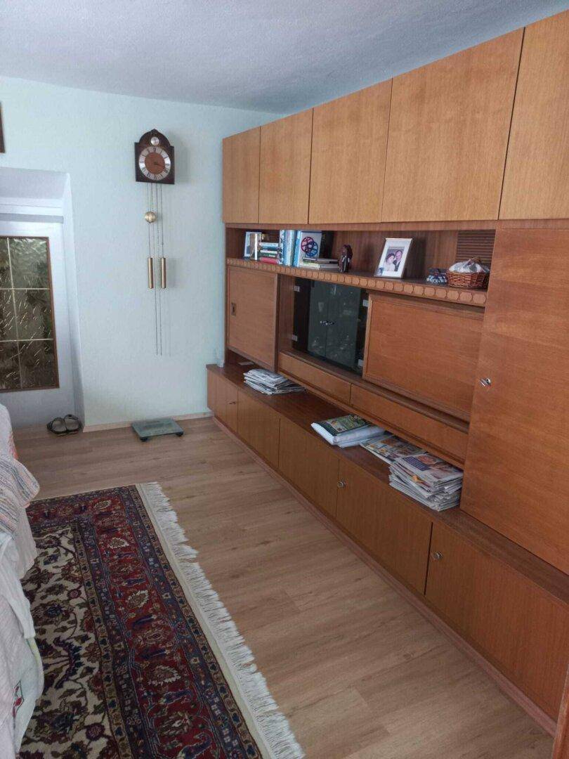 Wohnzimmer mit großer Holzschrankwand, Teppich und Laminatboden.
