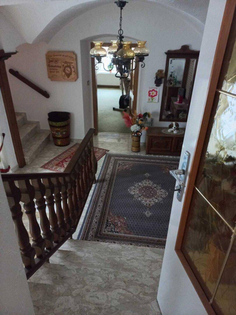 Traditioneller Eingangsbereich mit Steintreppe, Gewölbedecke und Kronleuchter.