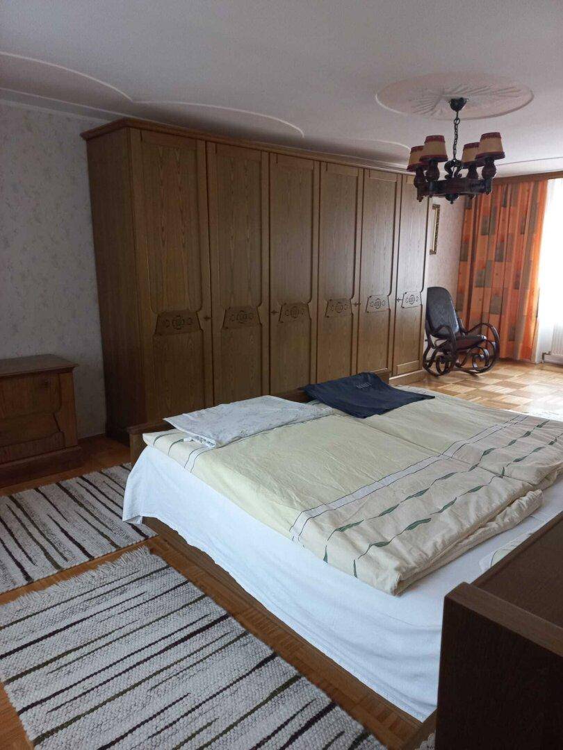 Schlafzimmer mit großem Holzschrank, Doppelbett und gemustertem Teppich.
