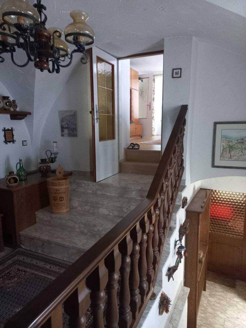 Treppenhaus mit Holzgeländer, Steinstufen und traditioneller Dekoration.