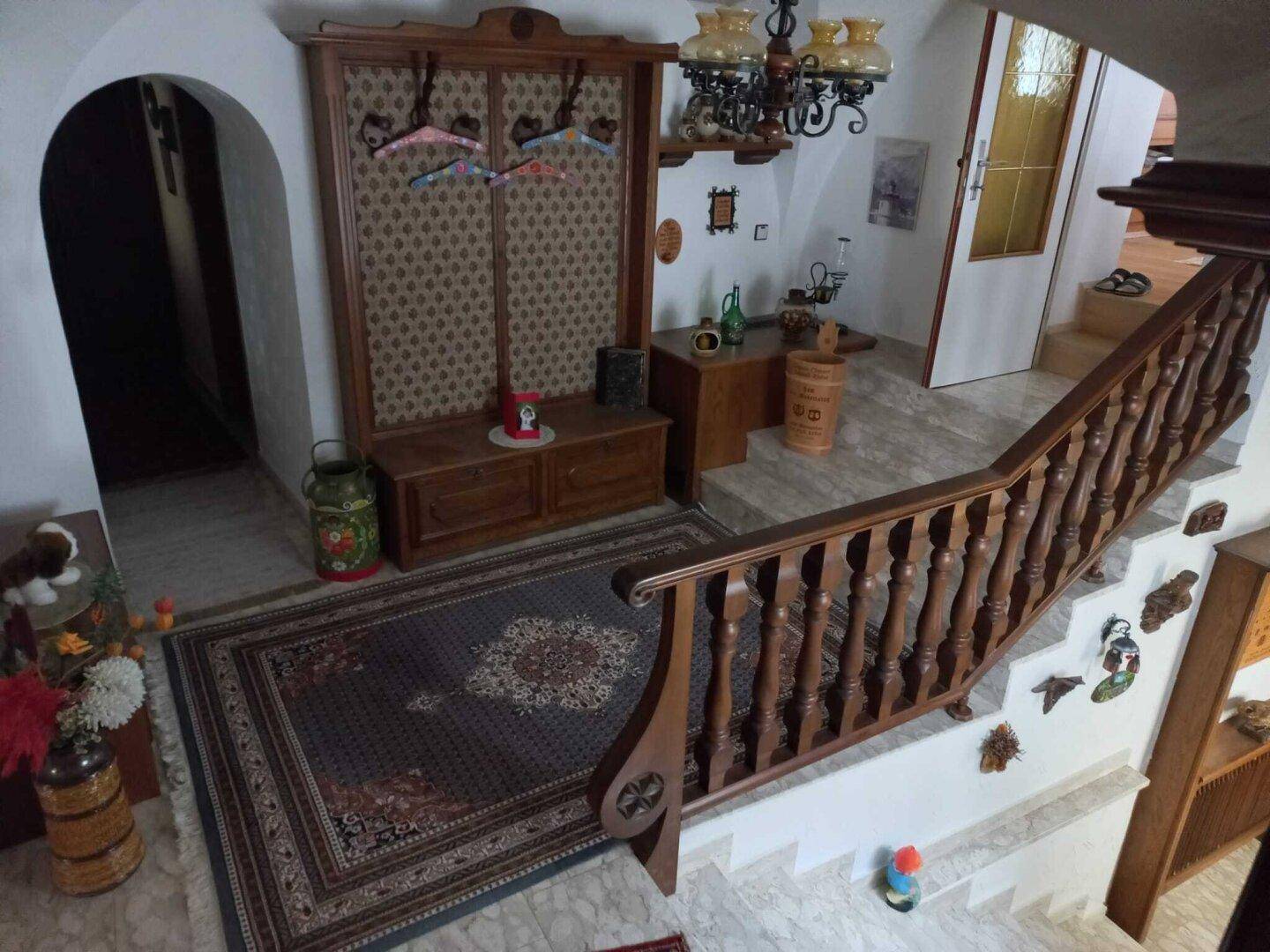 Geräumiger Eingangsbereich mit Holztreppe, Garderobe und traditionellem Teppich.