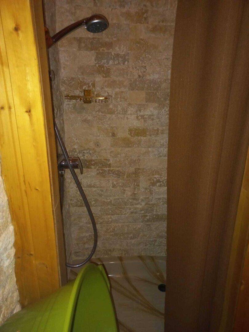 Einfache Duschkabine mit gefliesten Wänden und Duschvorhang.
