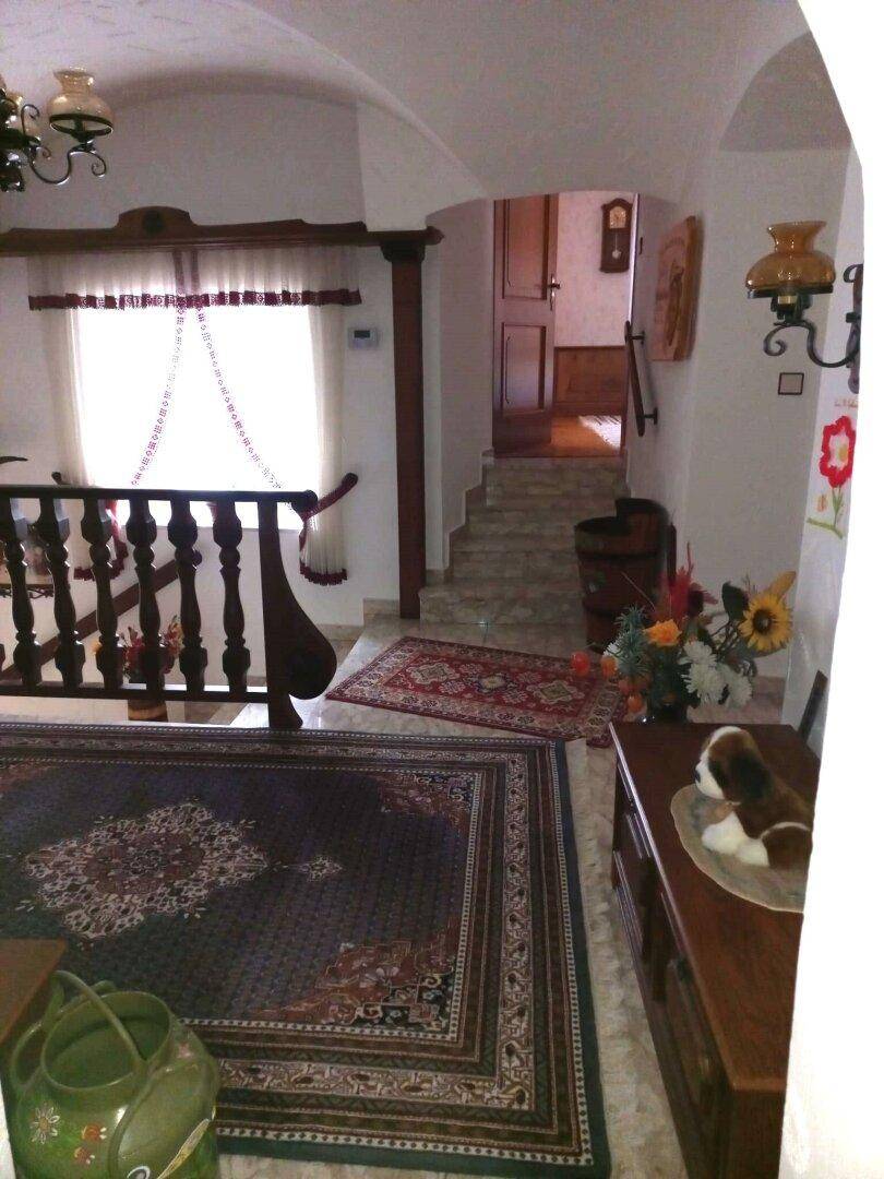 Heller Flur mit Steintreppe, Teppich und traditionellen Dekorationselementen.