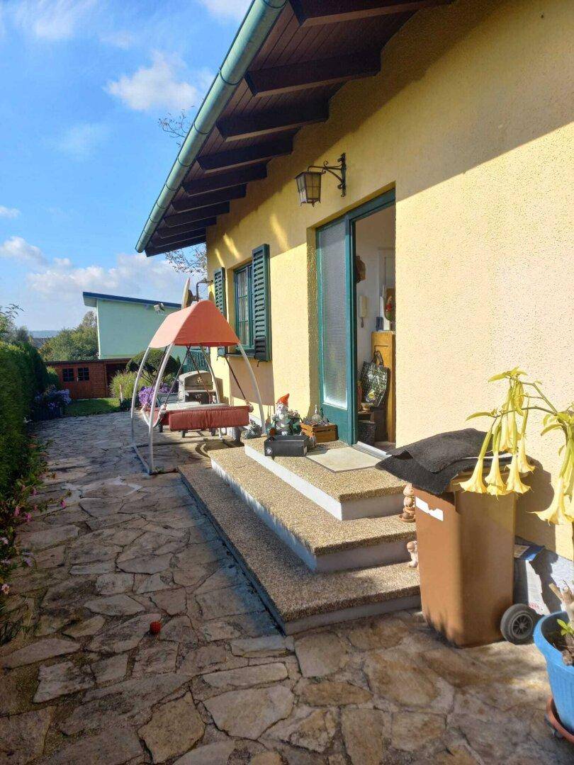 Seitlicher Zugang zum Haus mit Steinfliesenweg und einer kleinen Treppe zum Eingangsbereich.