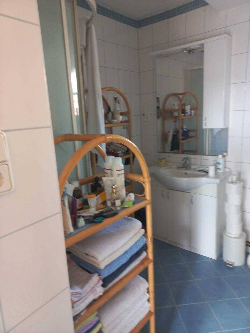 Helles Badezimmer mit Waschbecken, Spiegelschrank und blauen Bodenfliesen.