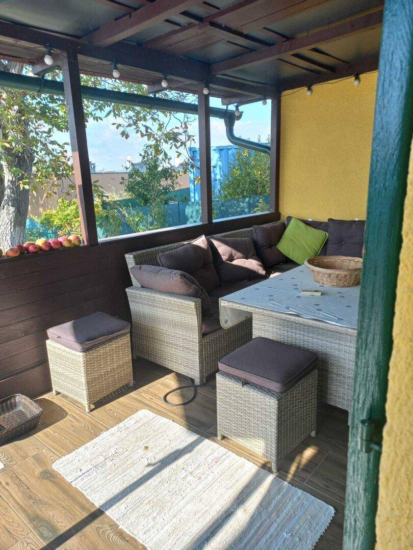 Überdachte Terrasse mit bequemen Rattanmöbeln und Blick ins Grüne, perfekt zum Entspannen.