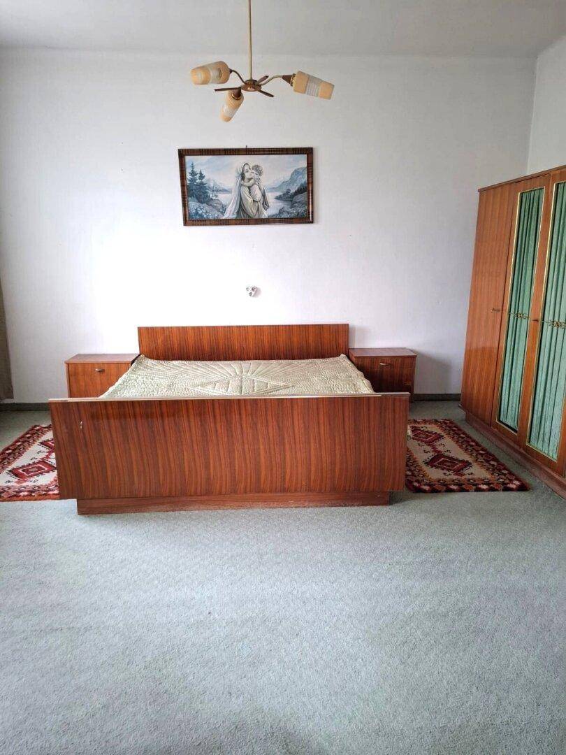 Schlafzimmer mit einem Holzbett, passenden Nachttischen und einem großen Kleiderschrank mit Glasfronten.