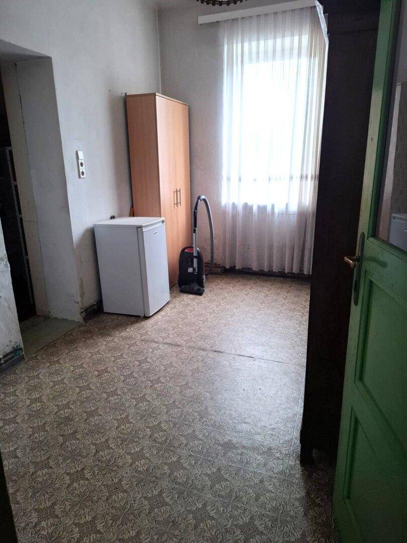 Nutzraum mit Vinylboden, einem Kühlschrank, Staubsauger und einem Kleiderschrank für zusätzlichen Stauraum.