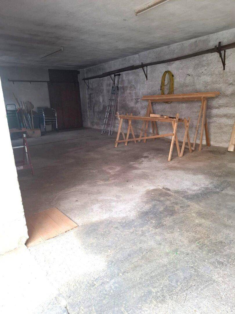 Geräumiger Garagen- oder Werkstattraum mit Betonboden und einfachen Holzböcken.