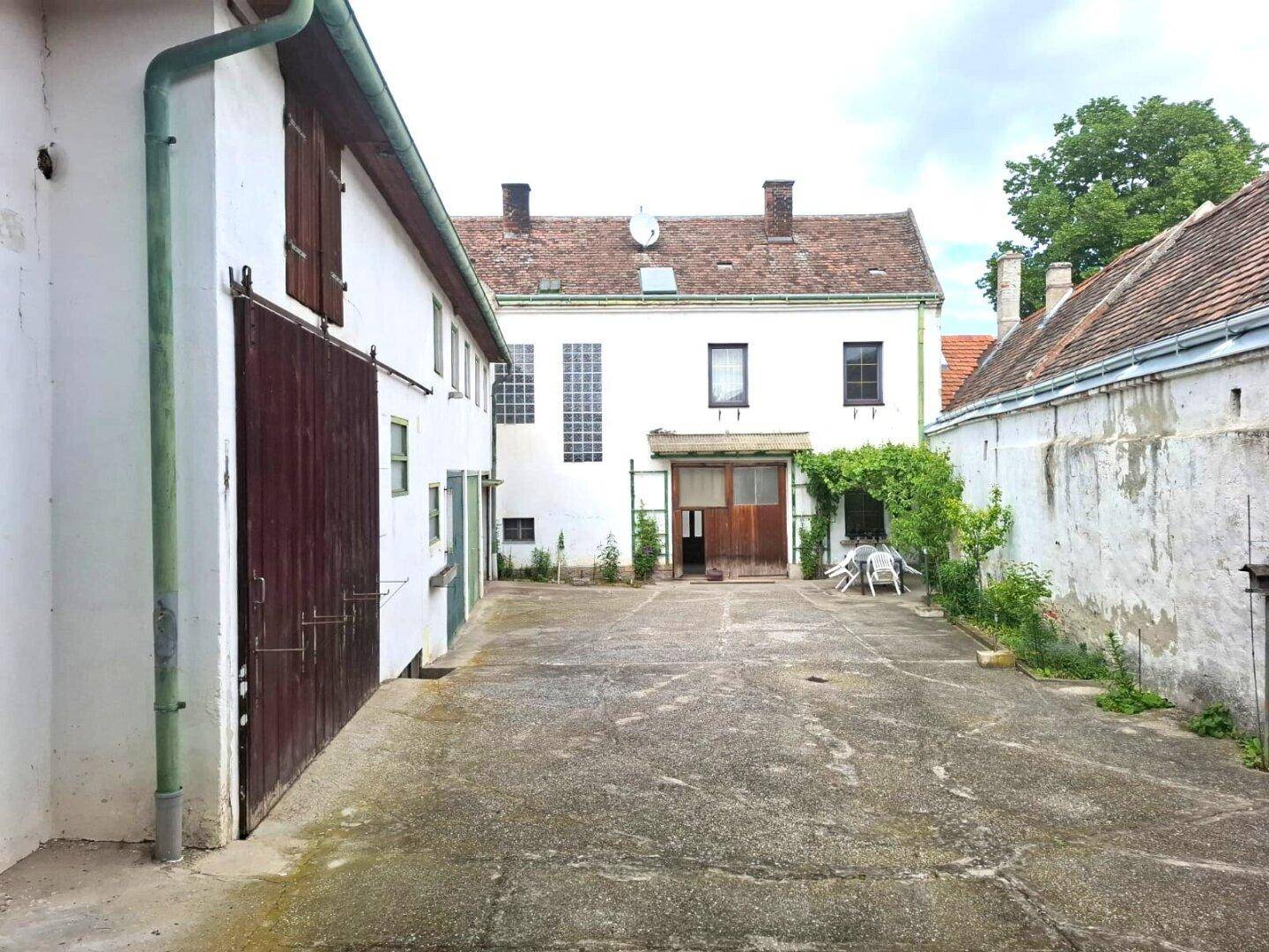 Blick auf den Innenhof mit der Hauptfassade des Gebäudes, Holztüren und Fenstern.