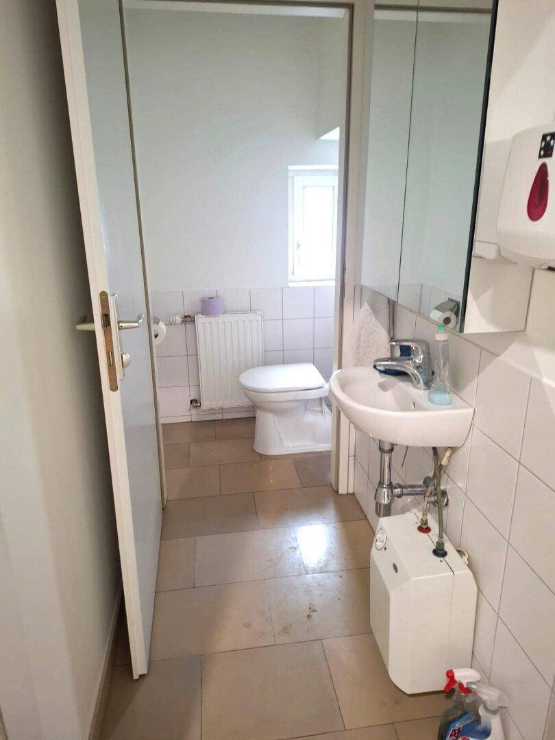 Kleines Badezimmer mit WC, Waschbecken und Fliesenboden, ausgestattet mit einem Fenster für Tageslicht.