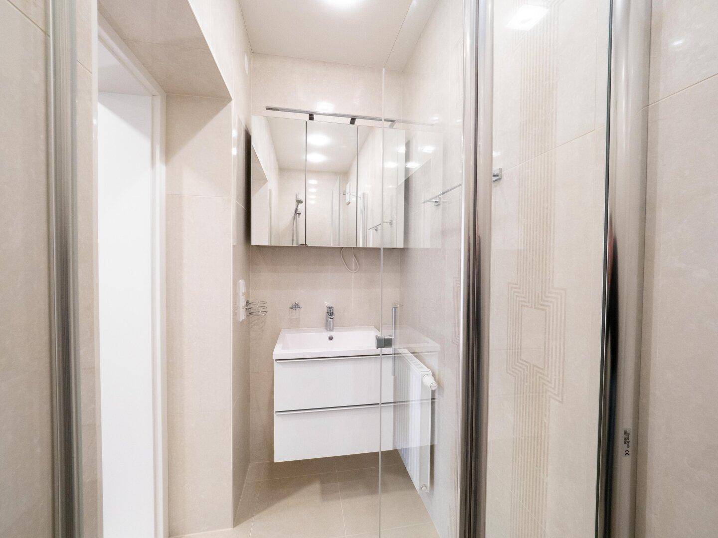 Modernes Badezimmer mit Duschkabine, schwebendem Waschtisch und Spiegelschrank.