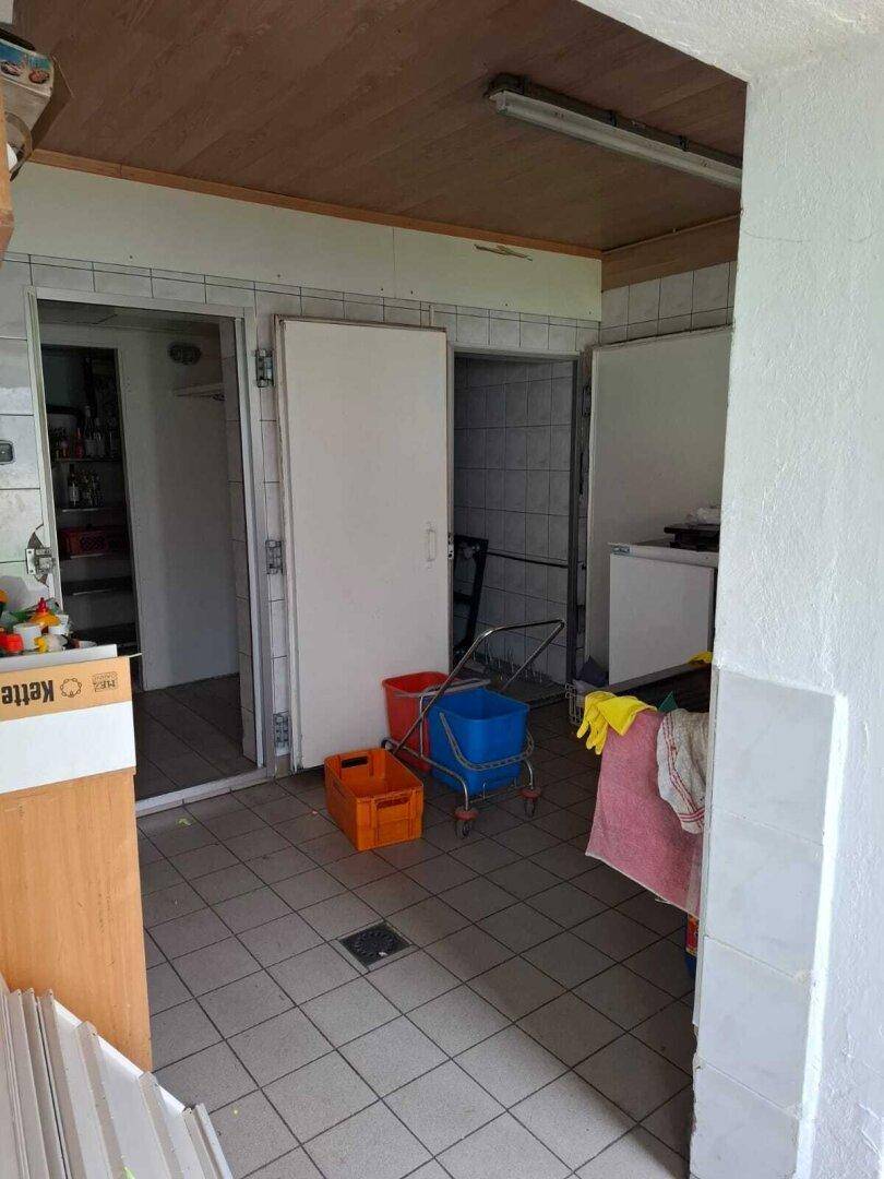 Praktischer Hauswirtschaftsraum mit Fliesenboden und Zugang zu mehreren Türen, der aufgeräumt werden muss.