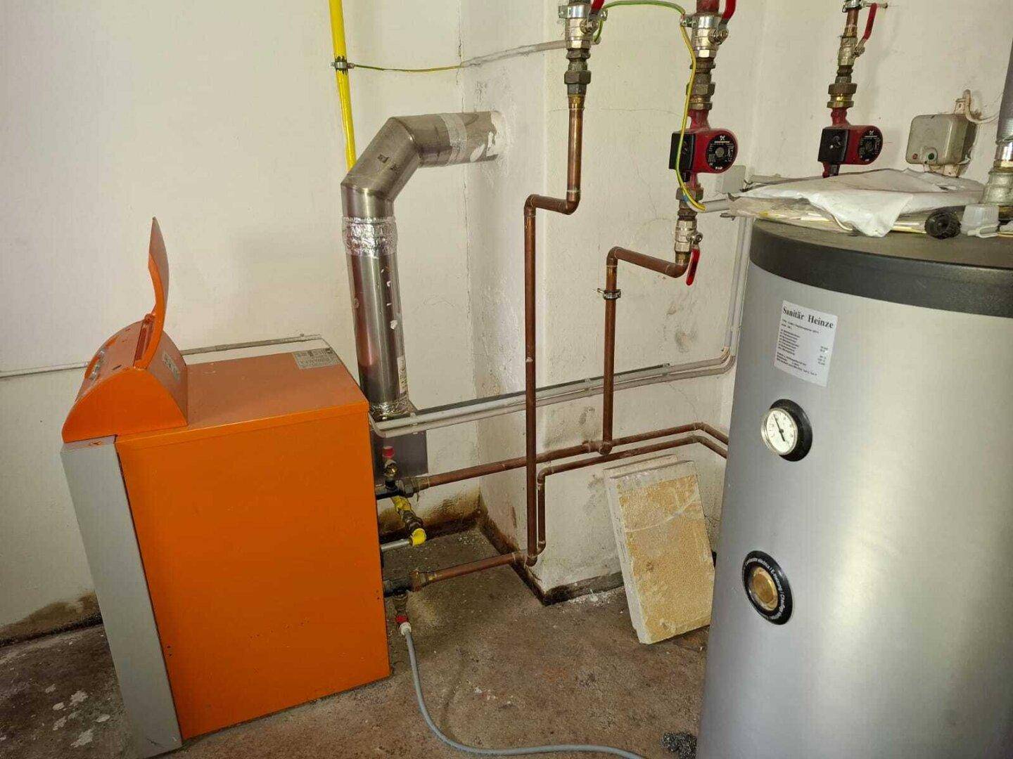 Heizungsraum mit Warmwasserspeicher und Heizkessel, der die Wärmeversorgung des Hauses sichert und älter ist.