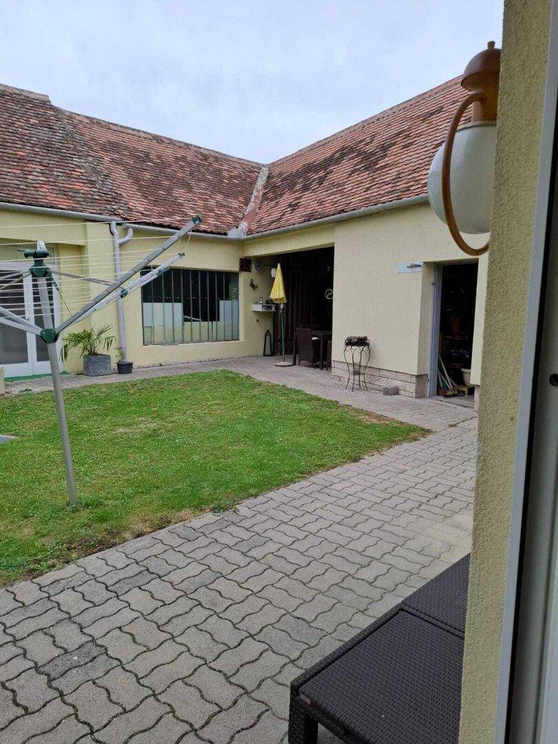 Gepflegter Gartenbereich mit Rasenfläche, gepflastertem Weg und Wäschespinne hinter dem Haus.