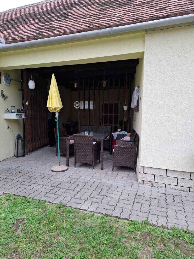 Überdachte Terrasse mit Gartenmöbeln und Sonnenschirm, ideal für entspannte Stunden im Freien.