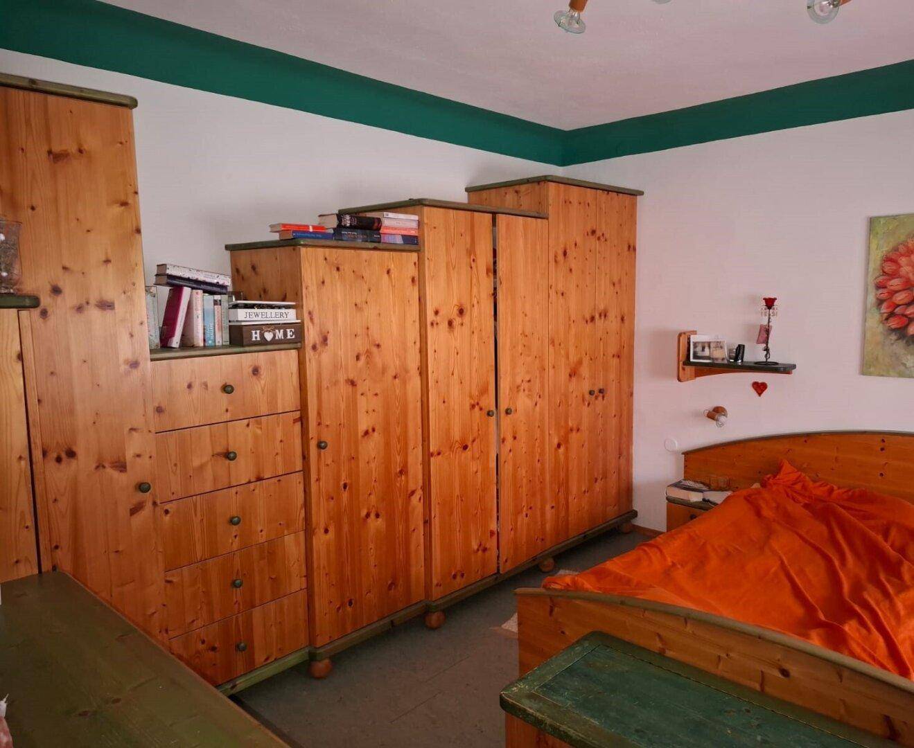 Schlafzimmer mit Holzmöbeln, Holzbett und grünen Akzenten, das eine gemütliche Atmosphäre schafft.