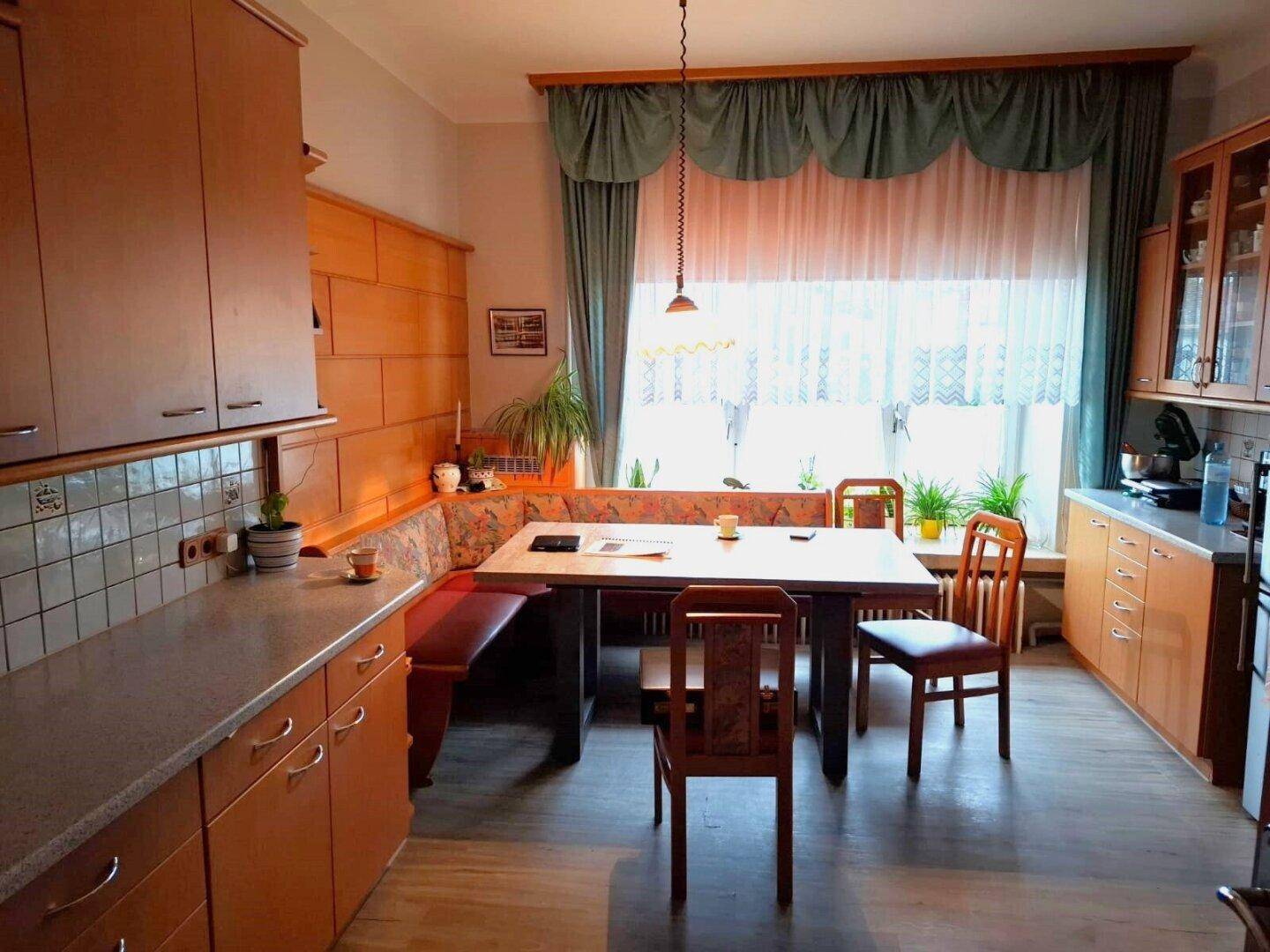 Geräumige Wohnküche mit Holzelementen, Esstisch und Blick in den Garten, die einen traditionellen Stil hat.