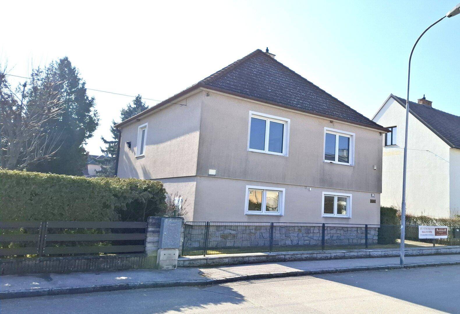 Ansicht des Einfamilienhauses von der Straße mit gepflegter Hecke und Vorgarten.