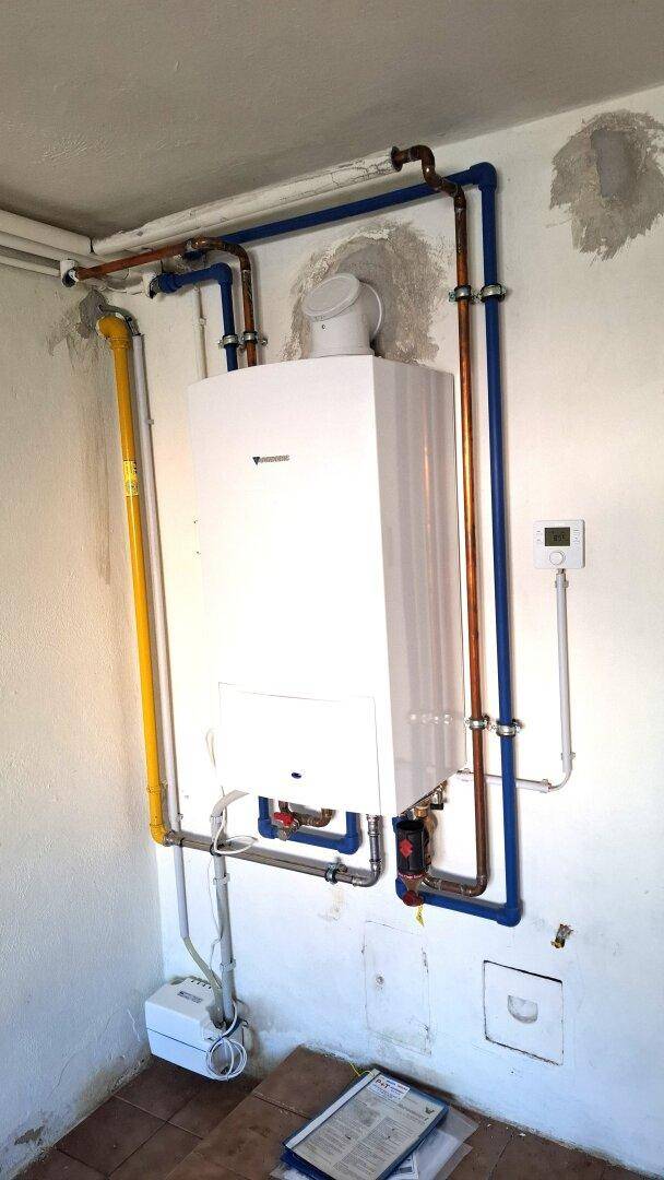 Hauswirtschaftsraum mit Heizungsanlage und sichtbaren Rohrleitungen an der Wand.