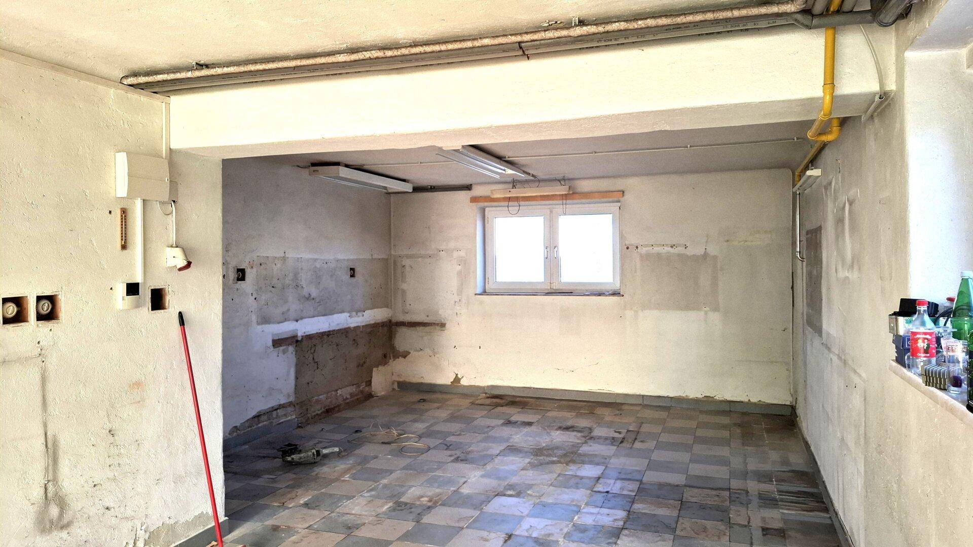 Unfertiger Raum mit Fliesenboden, Fenster und vorbereiteten Wänden für weitere Installationen.