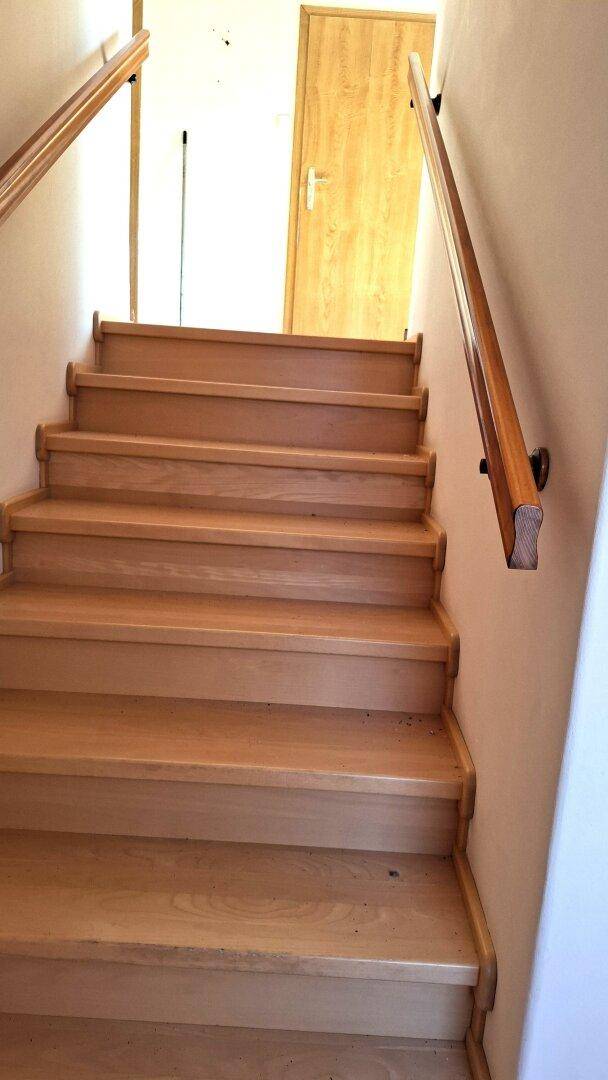 Massive Holztreppe mit Handlauf, die zu einem oberen Stockwerk führt.