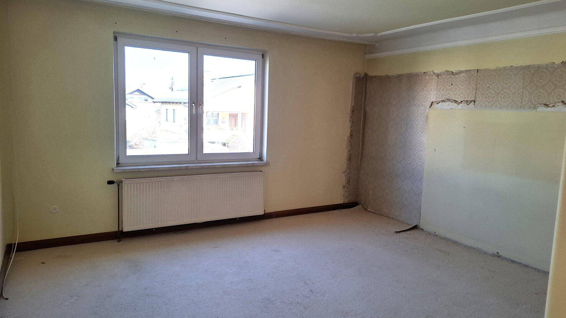 Schlafzimmer mit Teppichboden, Fenster und Heizkörper, bereit für Renovierung.