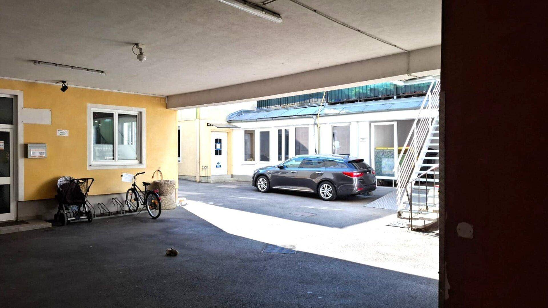 Innenhof mit Parkplätzen, Fahrrädern und dem Eingang zu einem Gebäude.