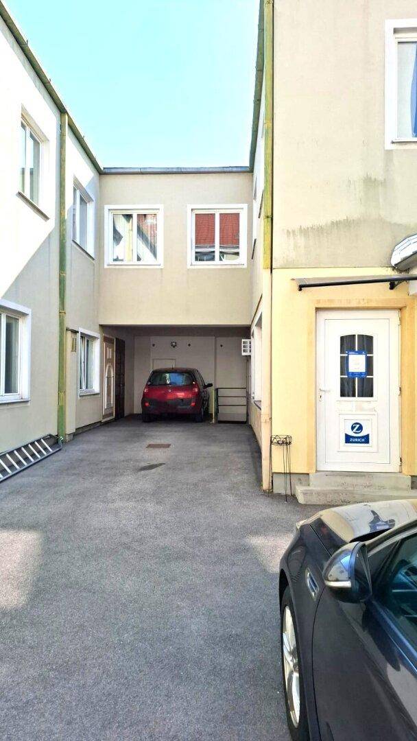 Innenhof mit geparktem Auto und verschiedenen Gebäudeeingängen.