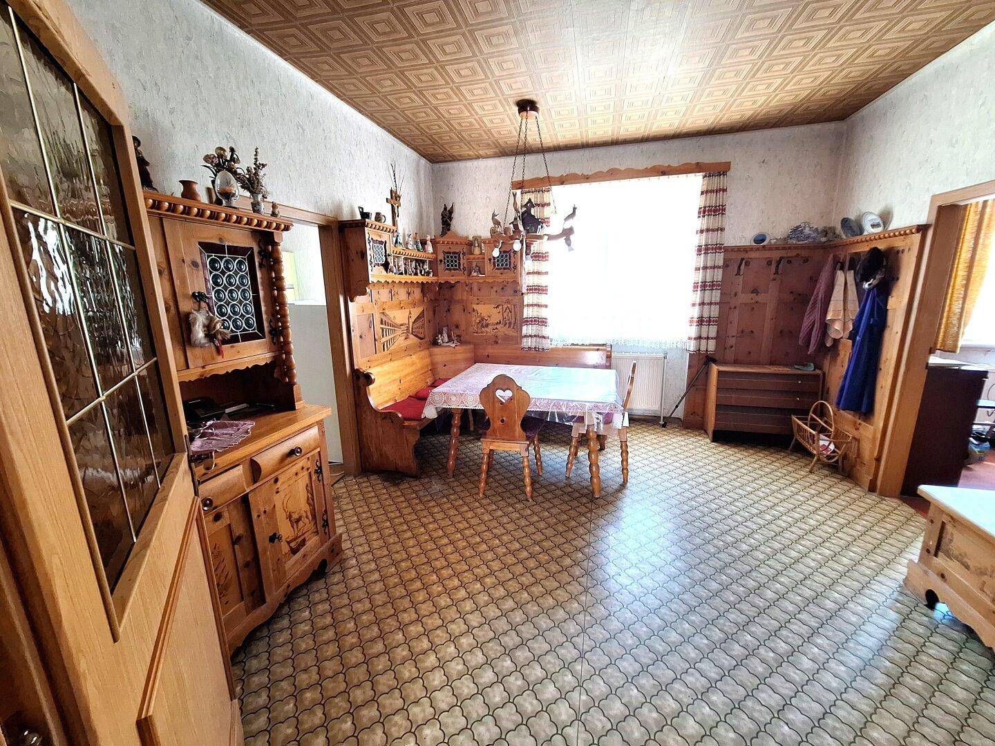 Gemütliches Esszimmer im alpinen Stil mit Holztäfelung, Eckbank und gemustertem Boden.