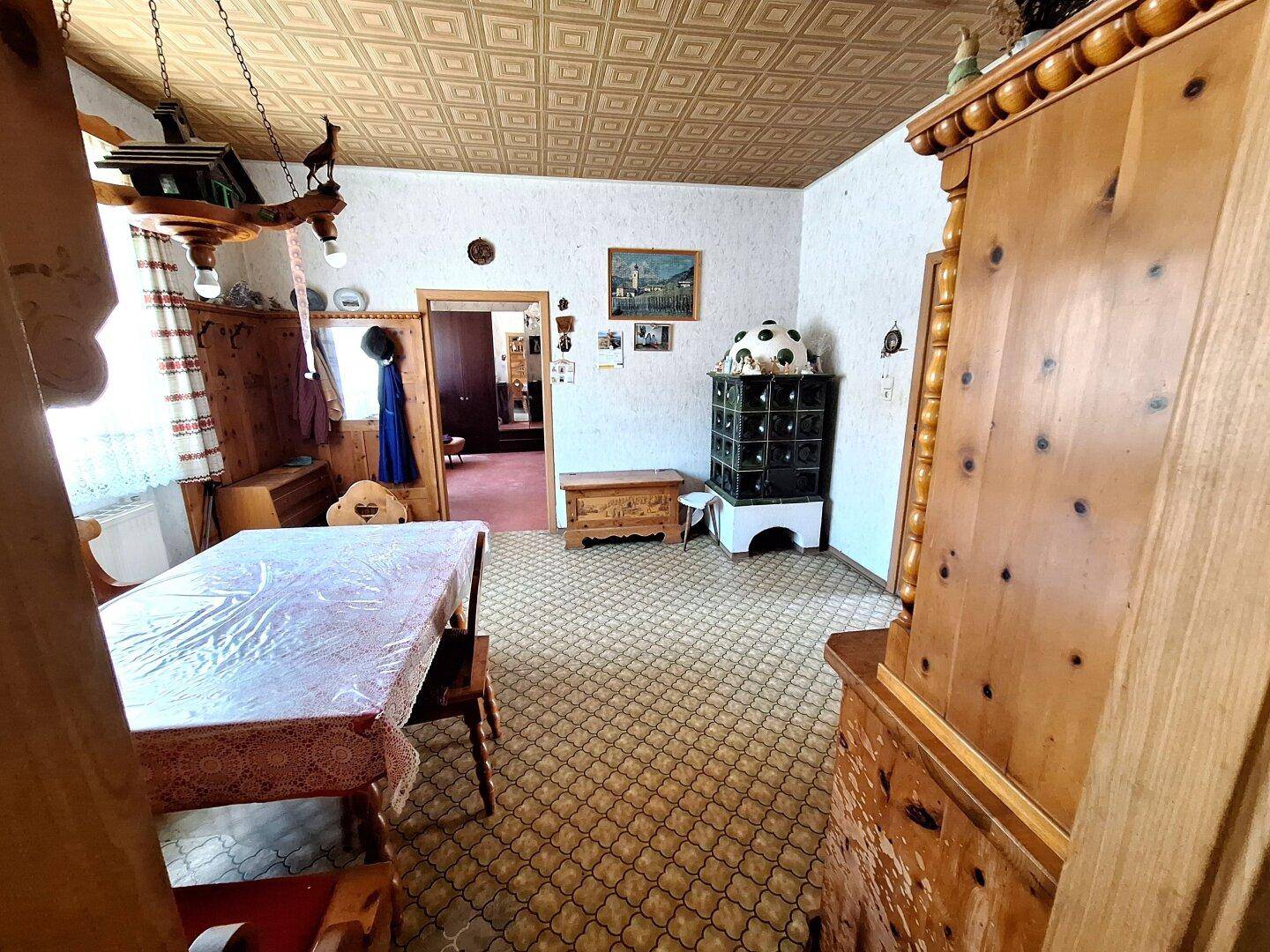 Traditionelles Esszimmer mit einem Kachelofen, Holztisch und gemustertem Boden.
