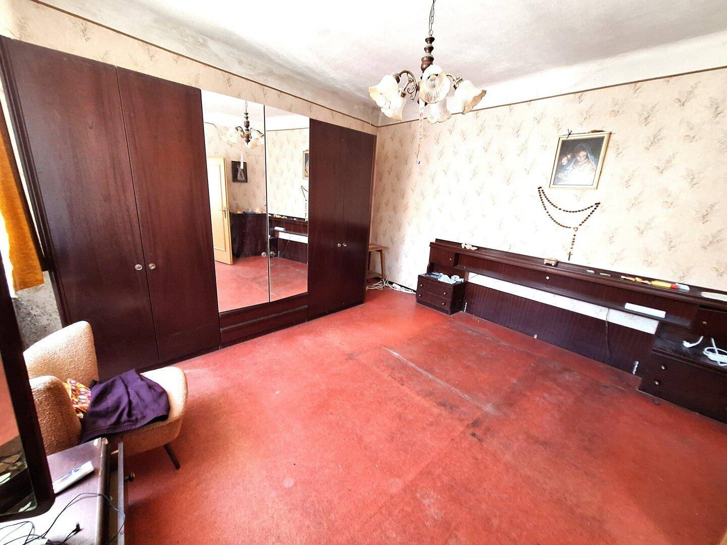 Schlafzimmer mit rotem Teppichboden, dunklen Holzschränken und einem großen Bett.