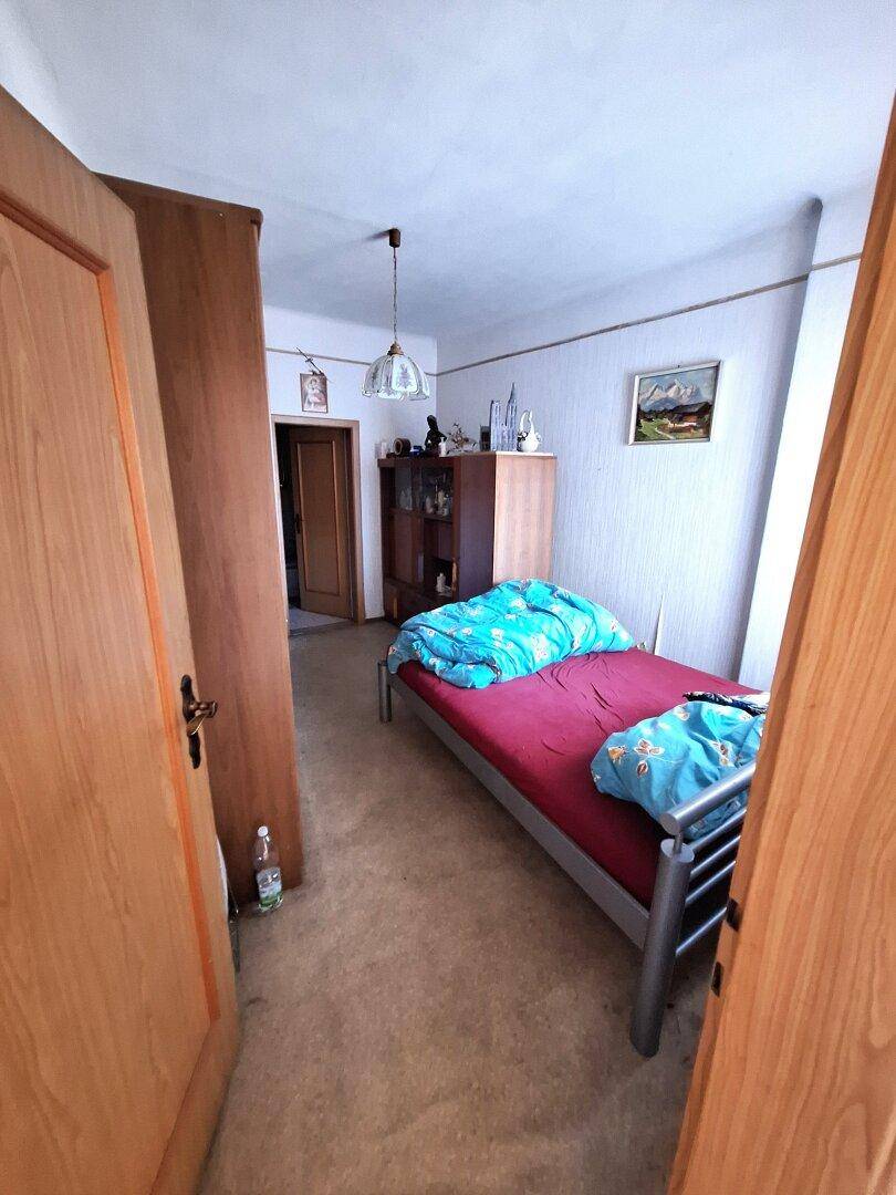 Kleines Schlafzimmer oder Gästezimmer mit Einzelbett und einfacher Einrichtung.