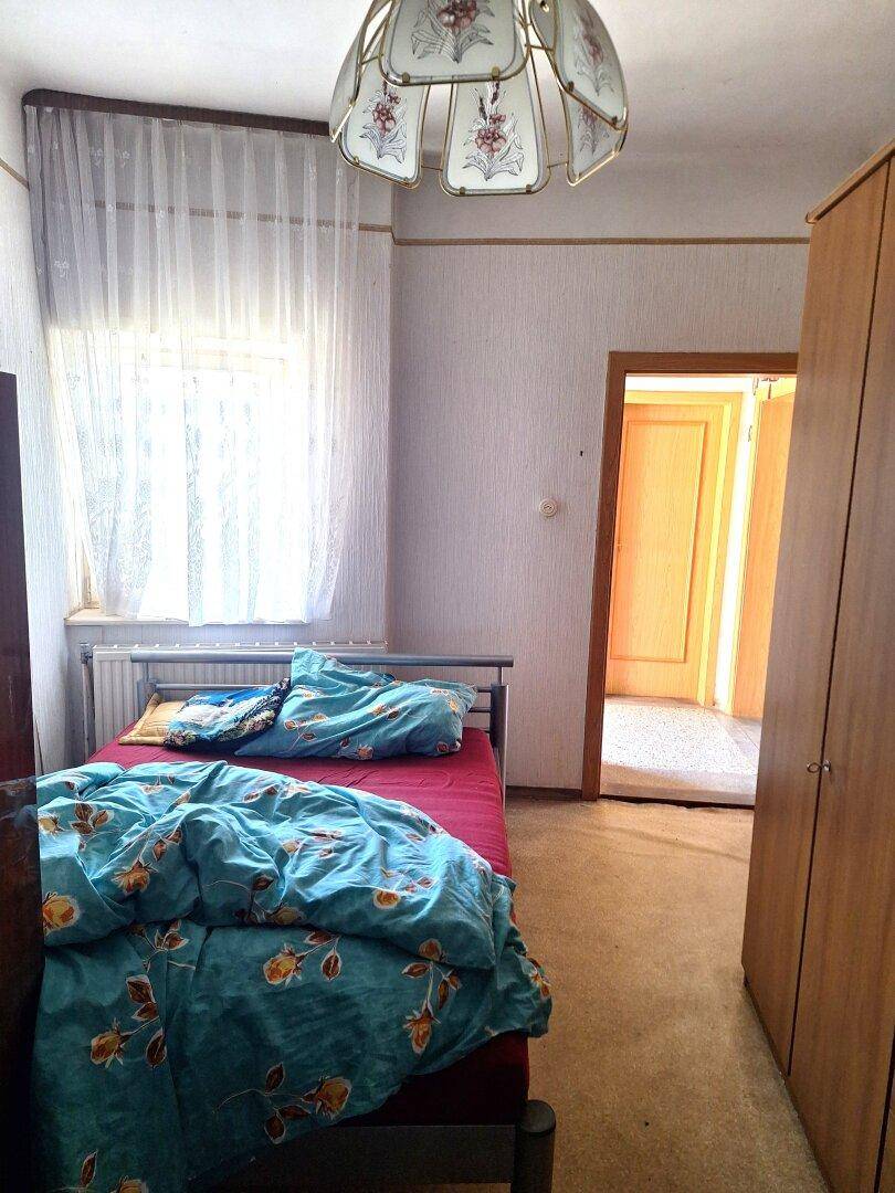 Helles Schlafzimmer mit einem Einzelbett, einem Fenster und einem Kleiderschrank.