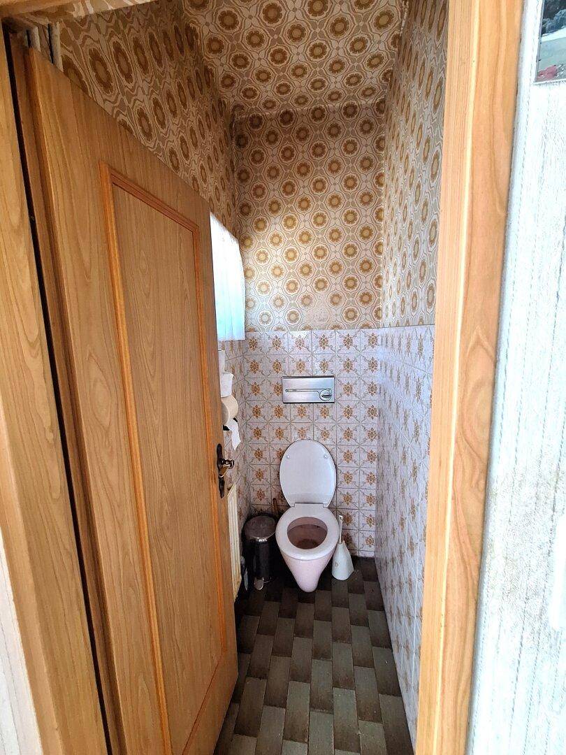 Kleines Gäste-WC mit gemusterten Fliesen und einer Toilette.