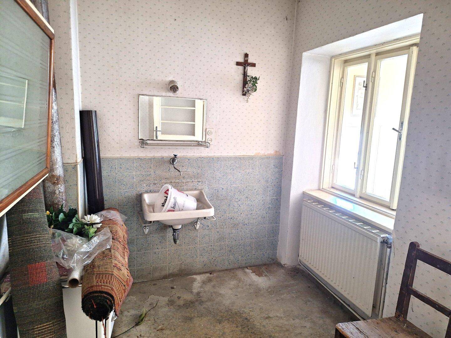 Rustikaler Raum mit Waschbecken, Fliesen und einem Fenster, das Tageslicht spendet.