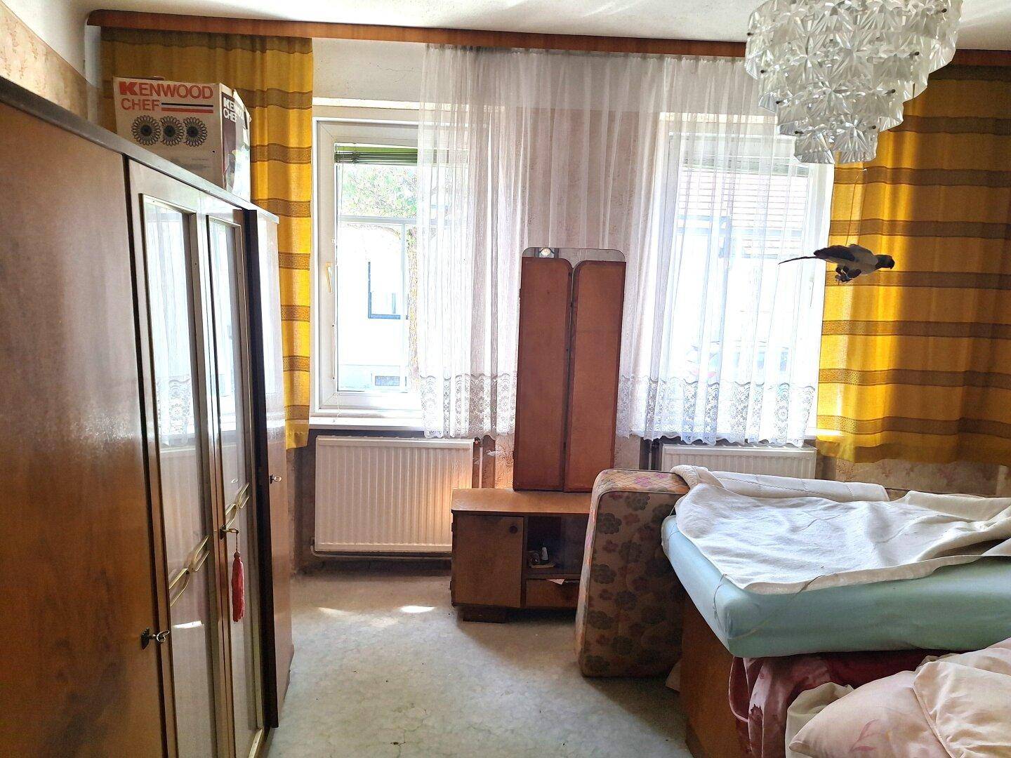 Schlafzimmer mit gelben Vorhängen, einem großen Kleiderschrank und einem Fenster.