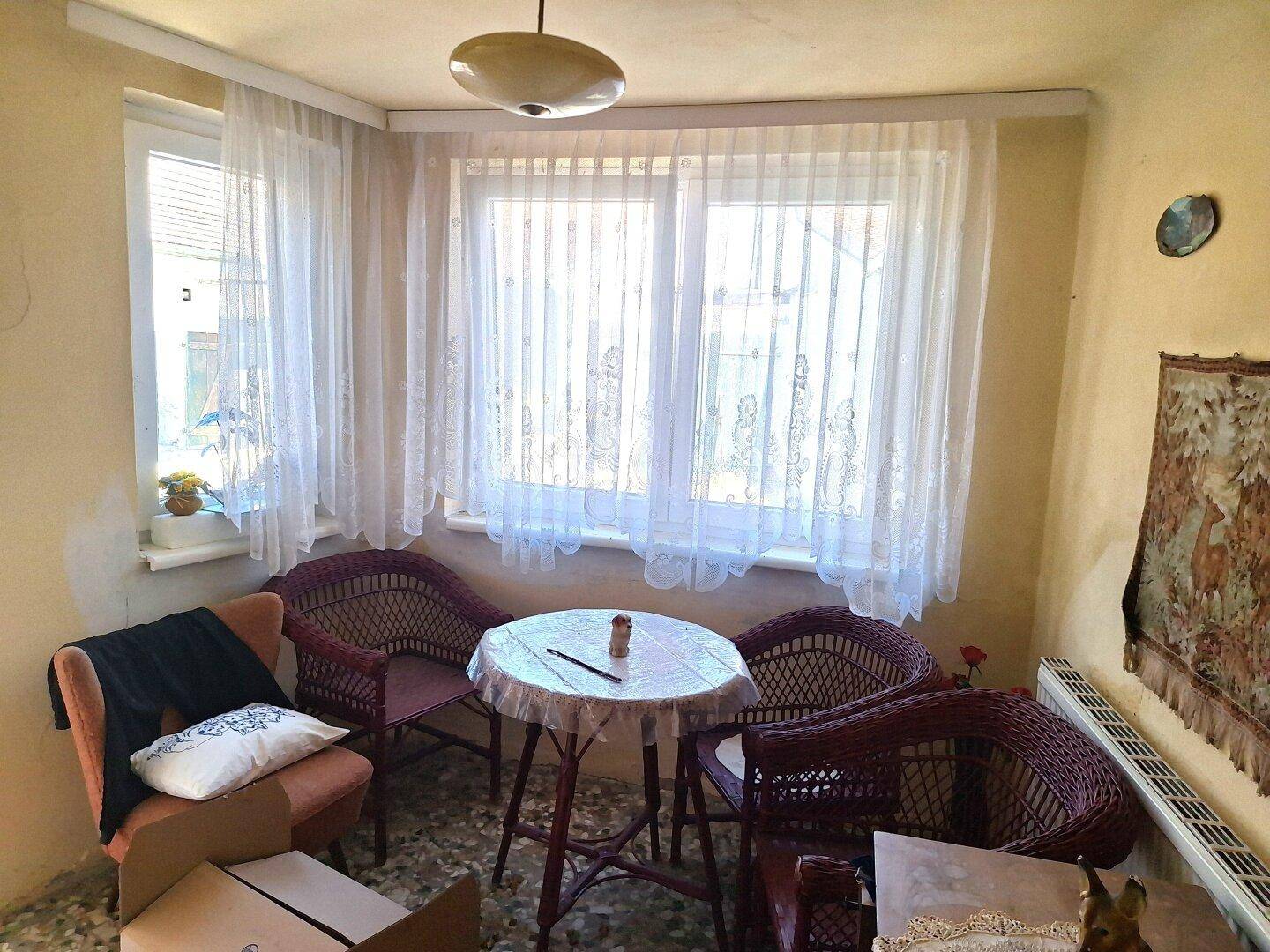 Heller Wintergarten oder verglaste Veranda mit Korbmöbeln und großen Fenstern.
