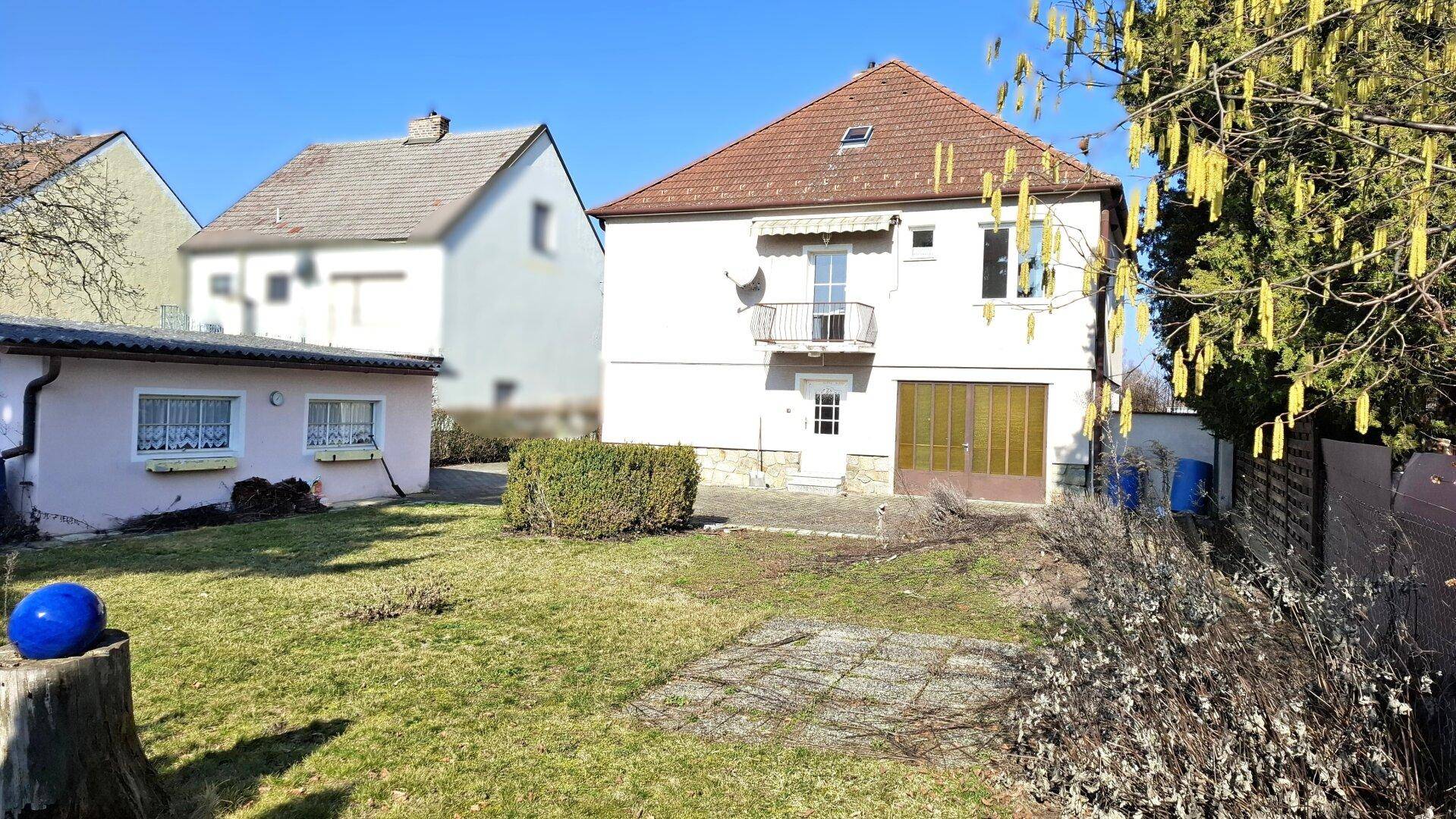 Rückansicht des Hauses mit großem Garten, Rasenfläche und einem kleinen Nebengebäude.