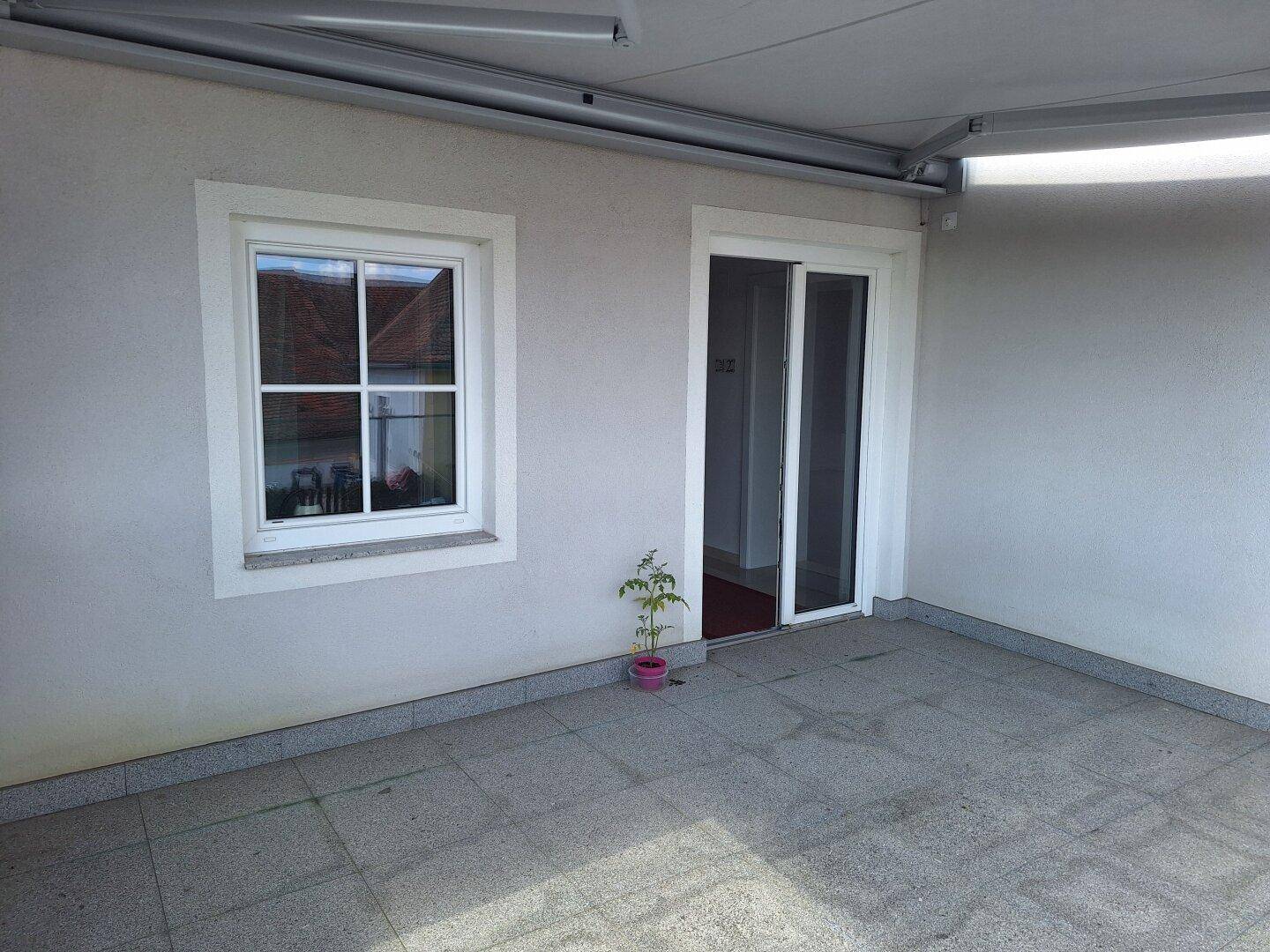 Geräumige, geflieste Terrasse mit Schiebetürzugang zum Innenbereich und einer Markisenstruktur.
