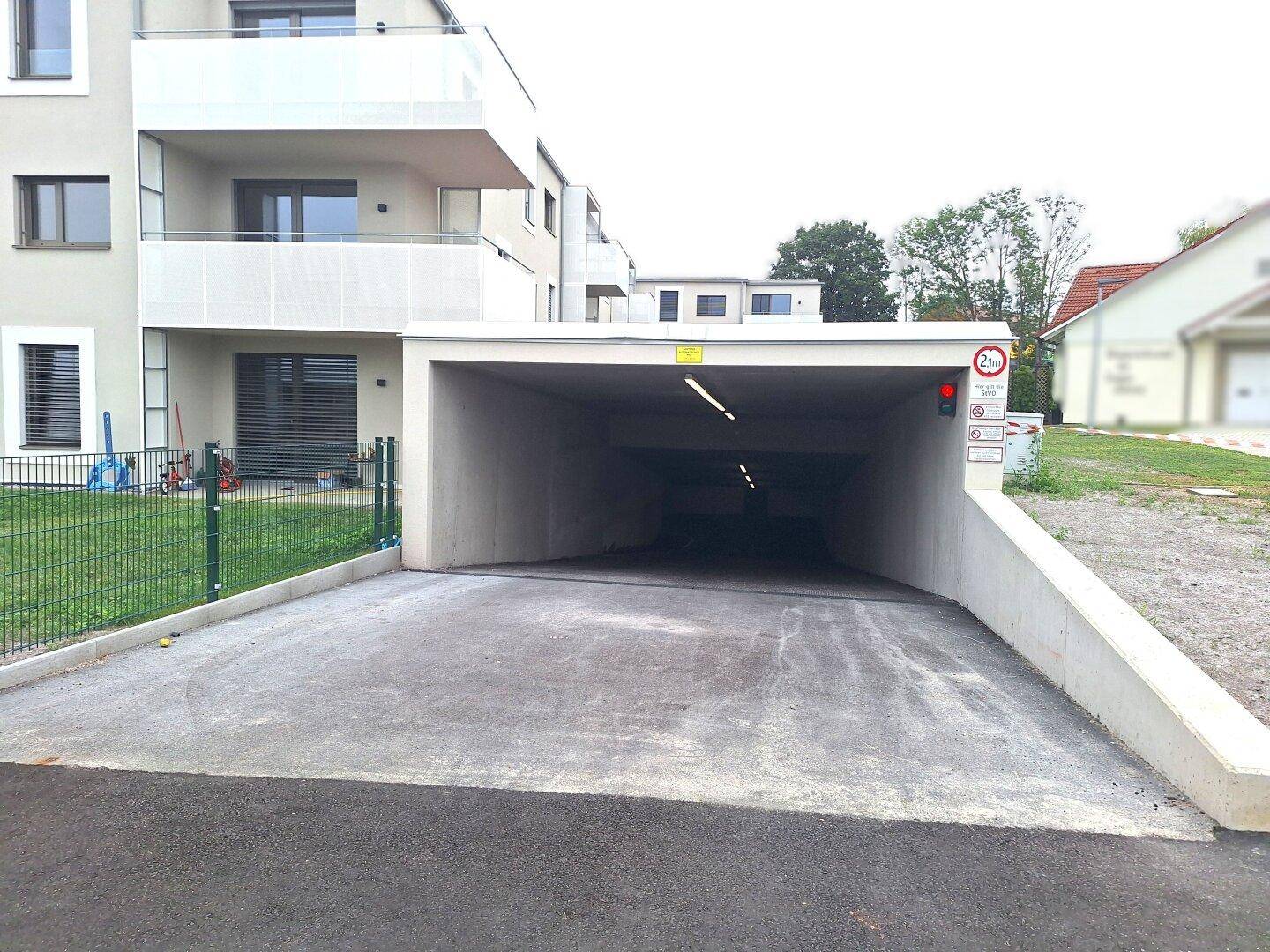 Eingang zur Tiefgarage eines modernen Wohngebäudes mit Höhenbegrenzung und Ampelsystem.
