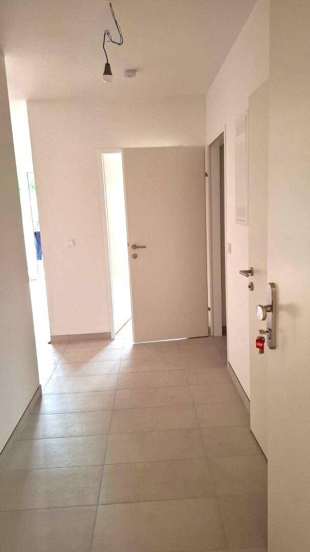 Heller Flur mit Fliesenboden und mehreren Türen, der zu verschiedenen Räumen führt.