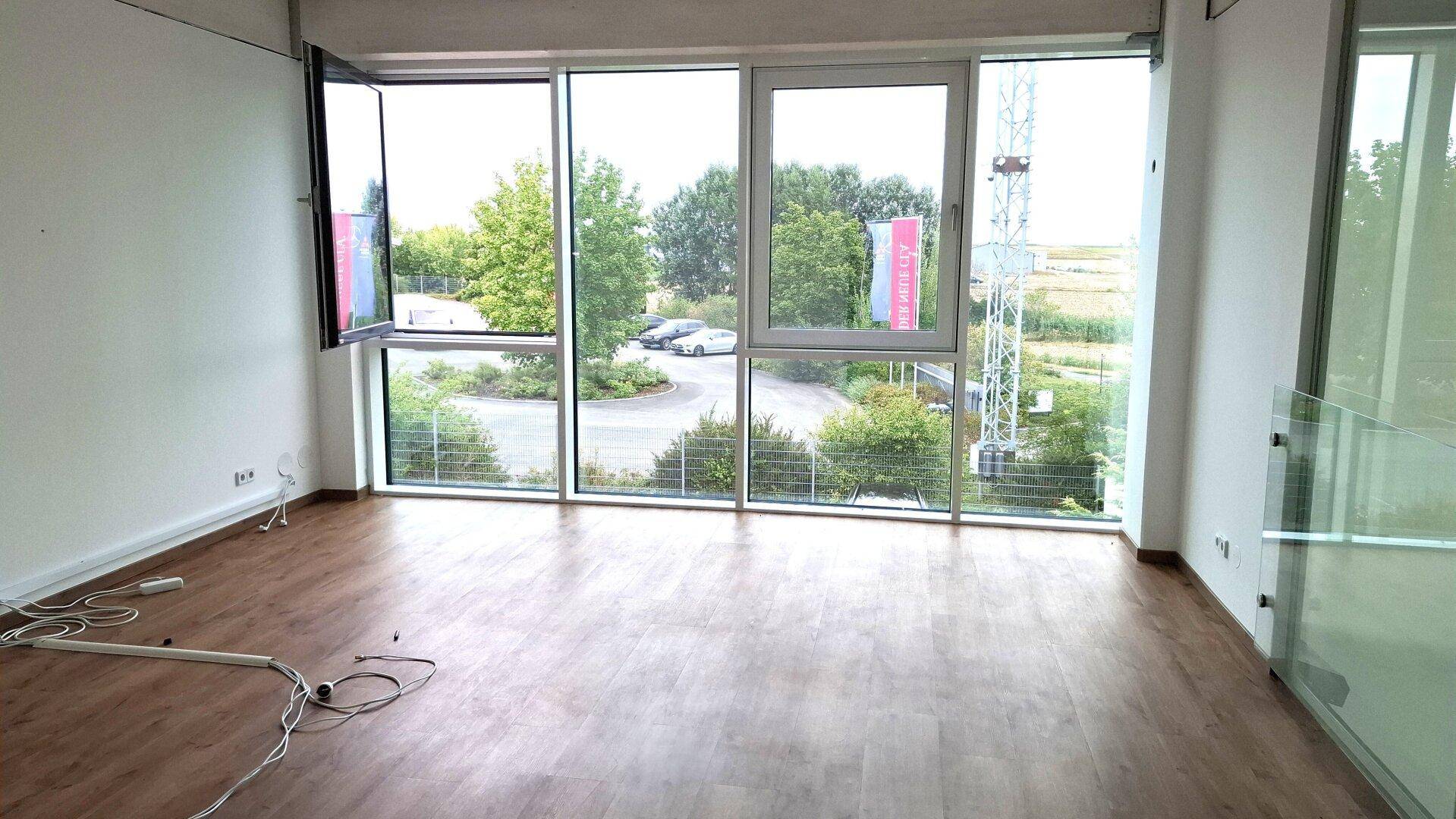 Helles Büro mit Laminatboden und großen Fenstern, die einen weiten Blick auf die Umgebung bieten.