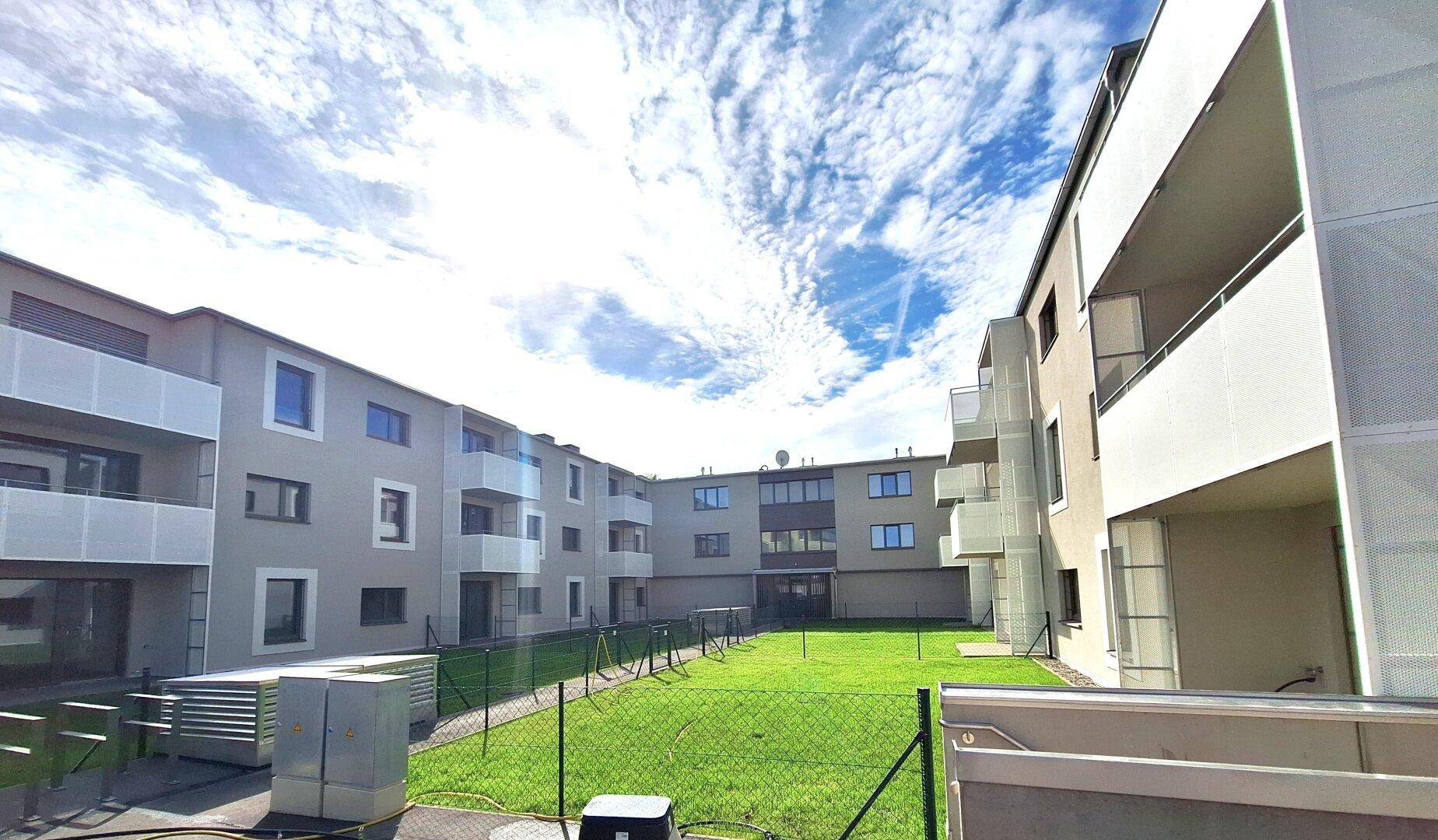 Blick auf die moderne Architektur des Wohnkomplexes mit Balkonen und einem gepflegten Innenhof.