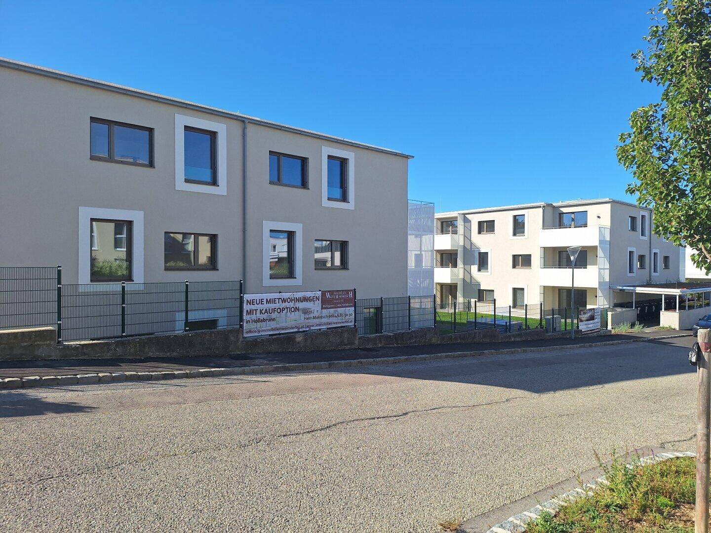 Gesamtansicht der modernen Wohnanlage von der Straße aus mit Werbebanner.