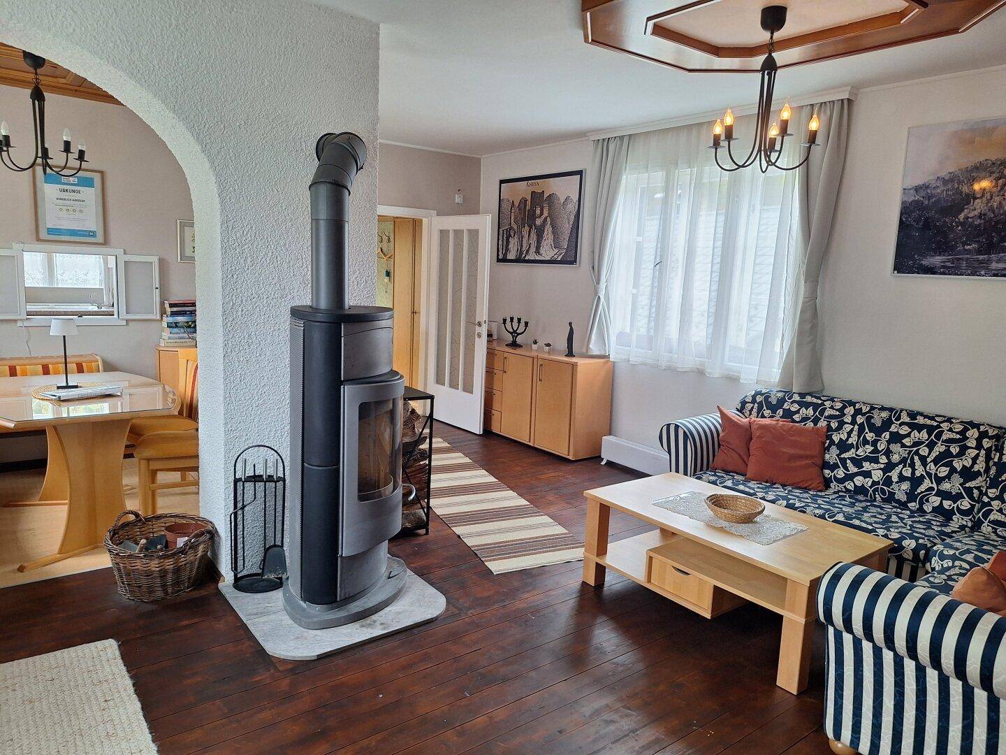 Heller Wohn- und Essbereich mit modernem Kaminofen, Holzboden und großen Fenstern für viel Licht.