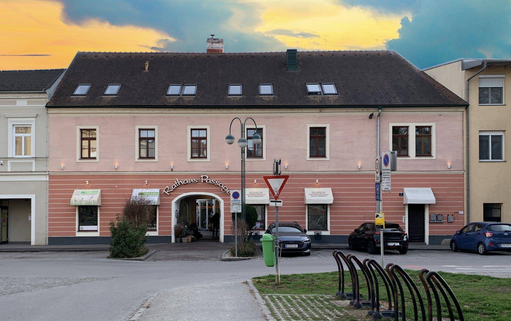 Historisches Gebäude mit rosa Fassade, Geschäften und einem Durchgang zur Rathaus Passage.